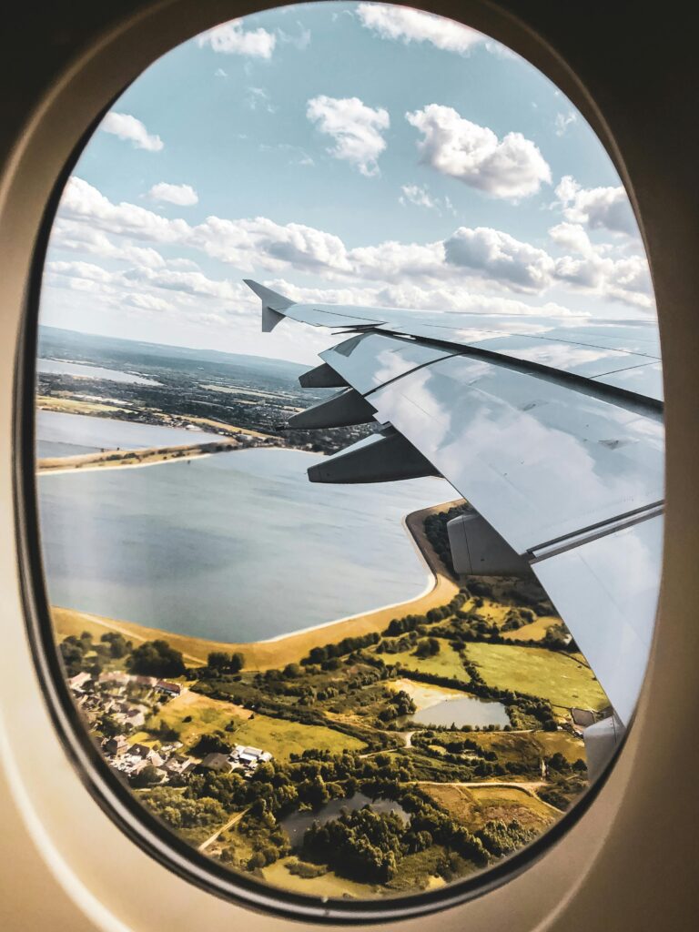 Scenic view of landscape through an airplane window with visible wing and sky.