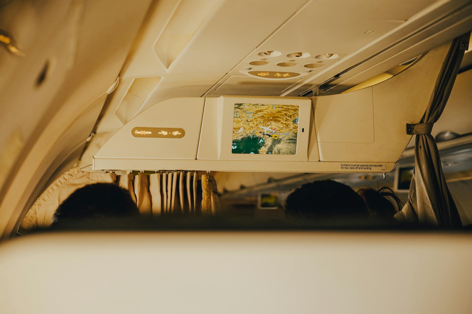 Interior view of a commercial airplane showing an in-flight entertainment screen and passenger seats.