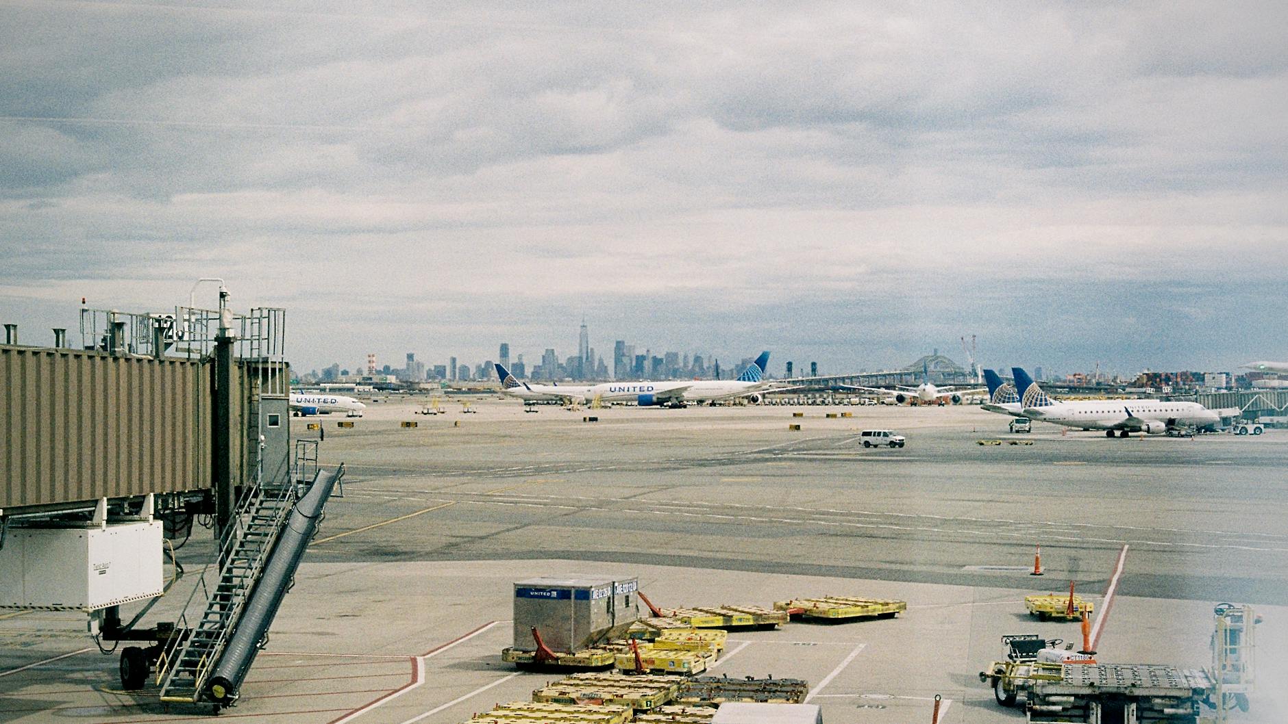 Aircraft waiting on JFK airport apron with New York City skyline in the background.